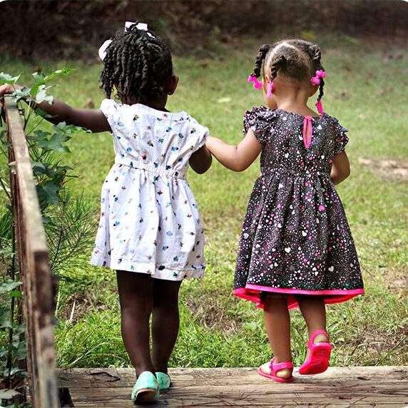 two girls holding hand together and walking