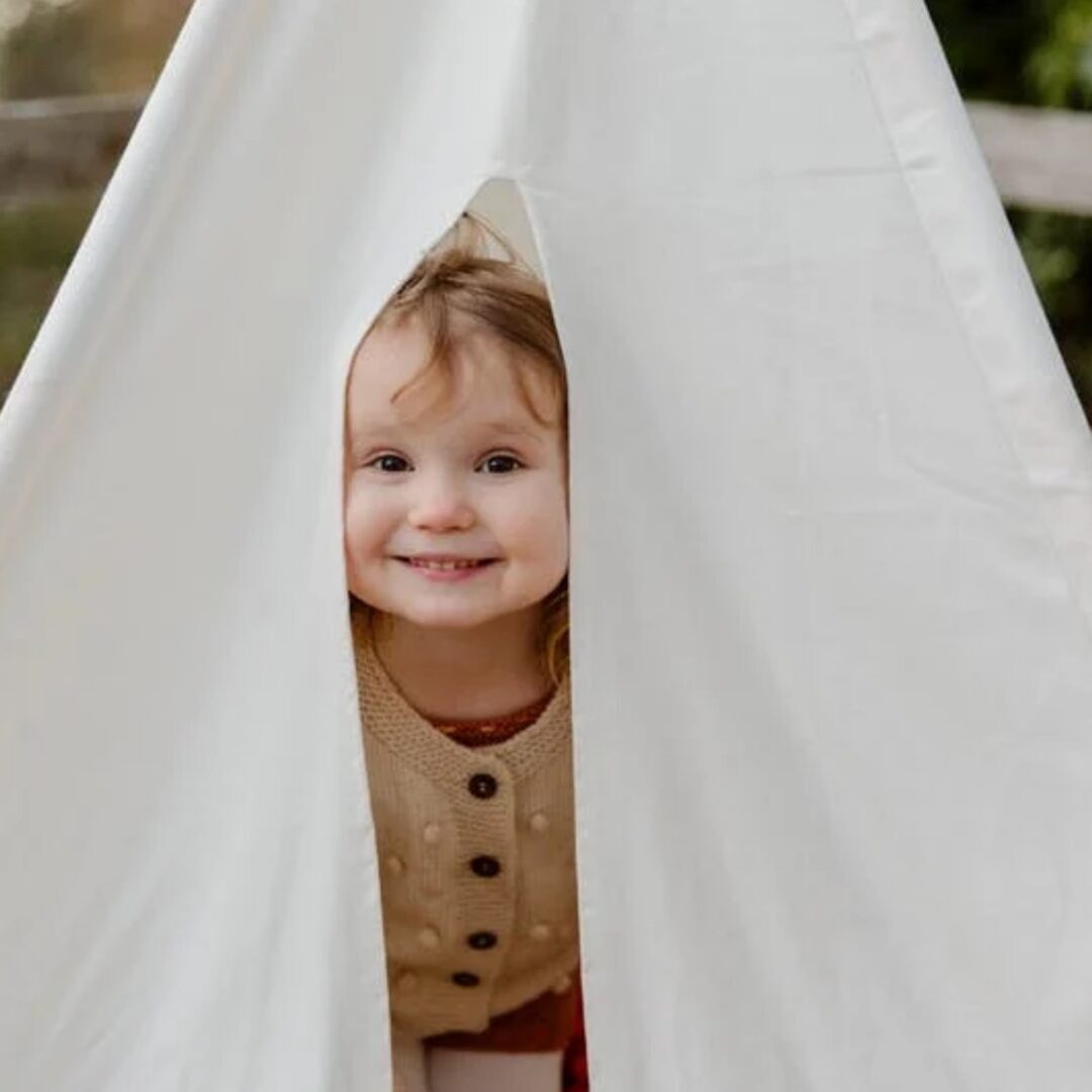 a young girl peeking out of tent